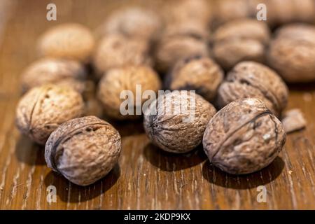 Heap of unpeeled walnuts on wooden table Stock Photo