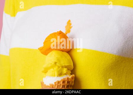 Close up an ice cream cone with three scoops of different flavor spilled a stain on clothes.  Stock Photo