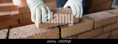 Male builder hands making make brickwork using red bricks Stock Photo