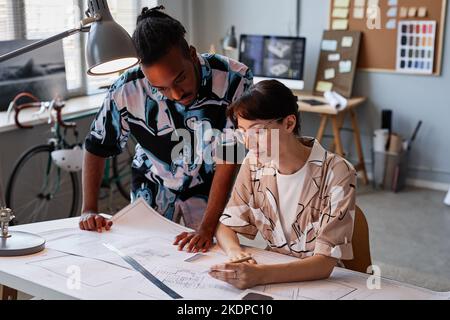 Portrait of two creative young people working on interior design project in office with dim lighting, copy space Stock Photo