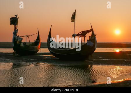 Landscape view at sunset of beautiful traditional wooden fishing boats known as moon boats on beach near Cox's Bazar in southern Bangladesh Stock Photo