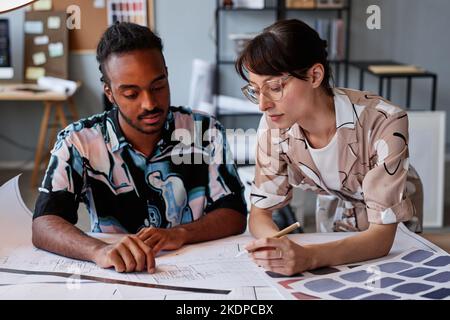 Portrait of two young architects working on floor plans for interior design project, copy space Stock Photo