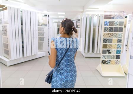 Girl into ceramic tiles shop. Back view. Stock Photo