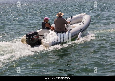 Couple in Brig Rigid Inflatable Boat RIB motoring to the entrance to Christchurch Harbour, known as The Run, Mudeford, Dorset UK in June Stock Photo