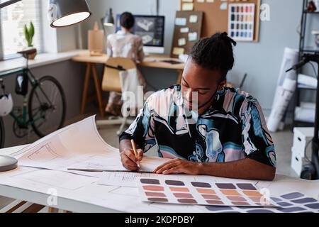 Portrait of creative black man working on floor plans for interior design project, copy space Stock Photo