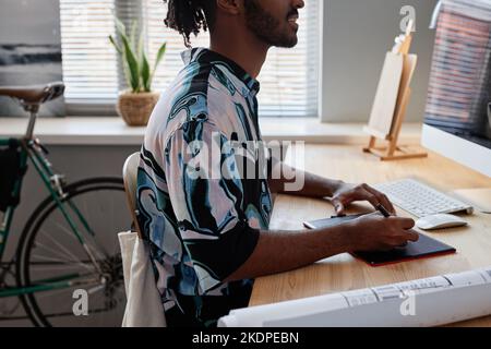 Side view closeup of young male designer using pen tablet at home office workplace Stock Photo