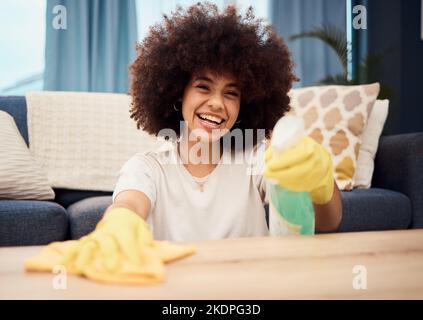 Happy, portrait and black woman cleaning dust on a table furniture with a cloth, liquid soap in a spray bottle and gloves. Cleaner, cleaning services Stock Photo