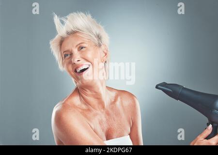 Hair, hairdryer and senior woman in studio for beauty, stylish and hair care on grey background mockup. Grey hair, mature woman and elderly woman Stock Photo