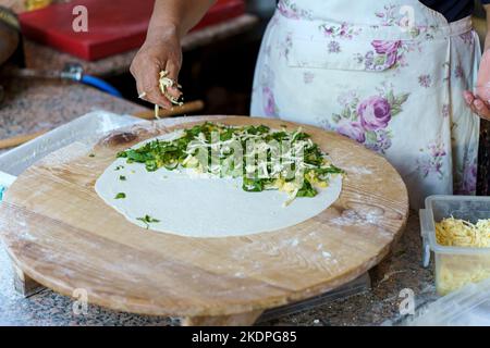 Turkish housewife cooking gozleme, traditional Turkish food cuisine. Gozleme stuffed with cheese and herbs. High quality photo. High quality photo Stock Photo