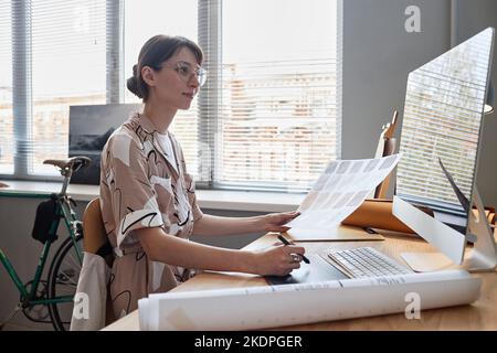 Side view portrait of young female designer focused at work in home office Stock Photo