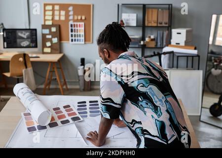 Back view portrait of male architect working on floor plans in office, copy space Stock Photo