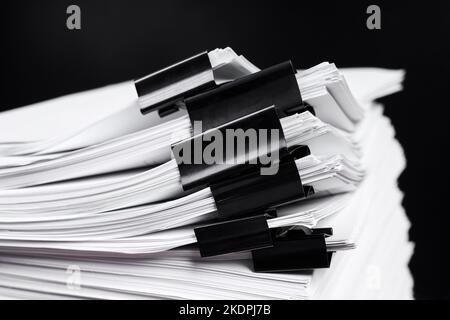 A stack of office papers, some of which are fastened with black binders Stock Photo