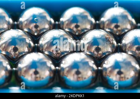 Balls from a ball bearing close-up in a row in oil, with reflections.Macro photo. Abstract background. Stock Photo