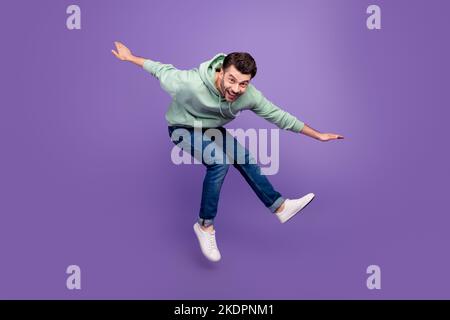 Full length profile portrait of satisfied glad person jumping toothy smile isolated on purple color background Stock Photo