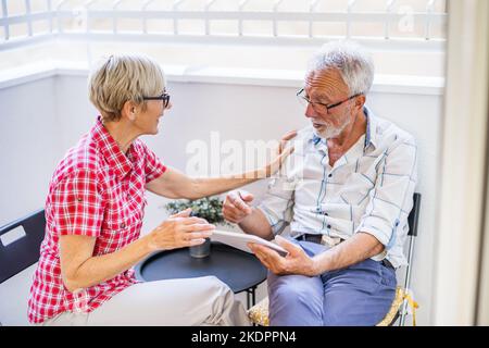 Senior couple sitting and talking on terrace at their home. Leisure time. Stock Photo