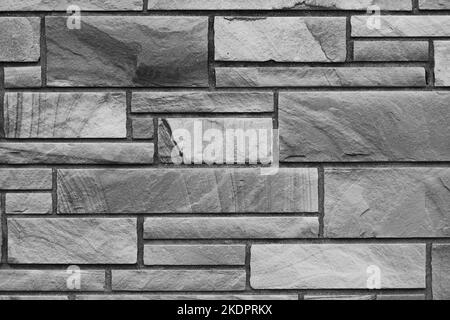Solid brick wall created with natural stone bricks in a random pattern with layers. Stock Photo