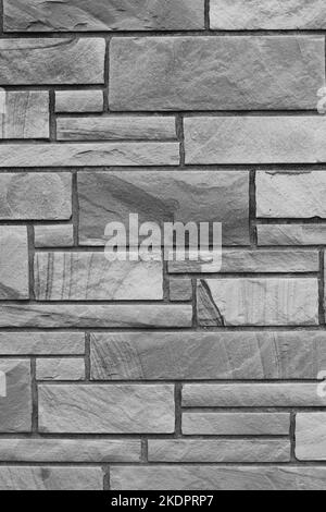 Solid brick wall created with natural stone bricks in a random pattern with layers in a black and white monochrome. Stock Photo