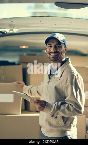 Our delivery service is completely digitised. Portrait of a delivery man using a digital tablet while checking the boxes in his van. Stock Photo