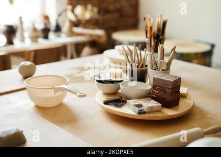 Still life background image of ceramic cups and art supplies on table in cozy pottery studio, copy space Stock Photo
