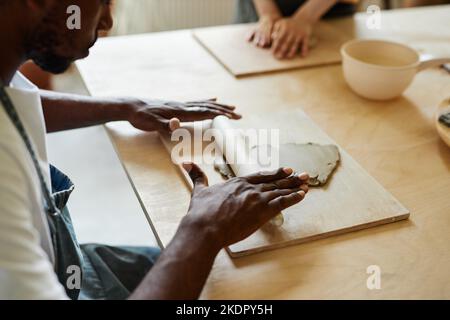 Close up of male hands shaping clay while enjoying art class in pottery studio, copy space Stock Photo