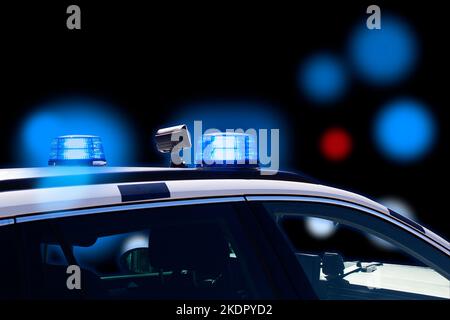 Police car at night with flashing lights and blurred bokeh blue and red lights on black background. Copy space. Stock Photo