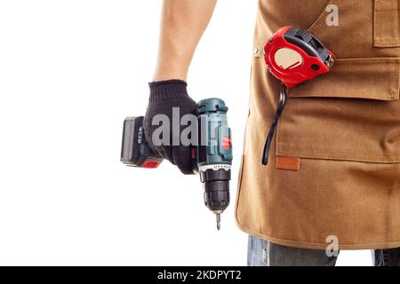 Man in apron and gloves holds cordless screwdriver on white background Stock Photo