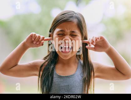 Going through her moods. a little girl covering her ears outside. Stock Photo