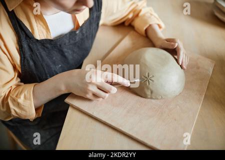 Closeup of female artist decorating handmade ceramic bowl in pottery studio, copy space Stock Photo