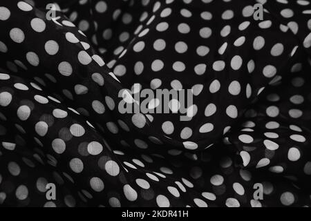 Gathered and folded texture of black and white polka dot printed fabric copy space.Folds form a wavy black texture. retro style photography concept. Stock Photo