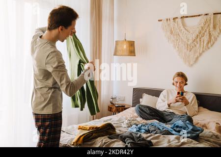 Young gay couple talking and smiling while doing housework at home Stock Photo