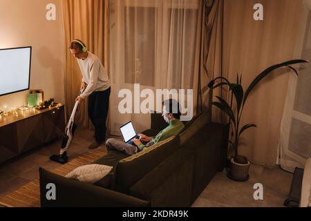 Young gay couple using laptop and doing housework at home Stock Photo