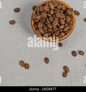 Cup with coffee beans on the background, spilled coffee beans near the cup, top view of coffee. Stock Photo
