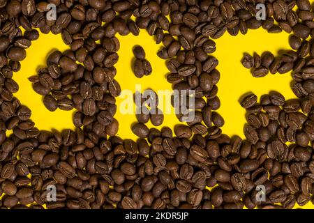The inscription of the word coffee on coffee beans, coffee on a yellow background. Stock Photo