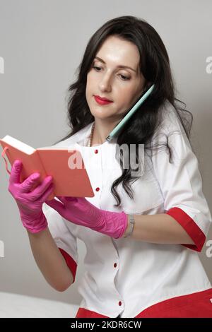 A beautician makes a note in a notebook and talks on the phone, a portrait of a beautician girl. Stock Photo