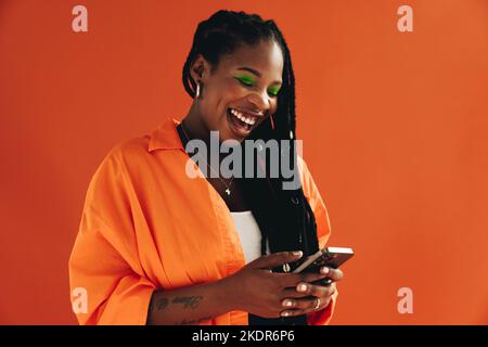 Happy young woman reading a text message on her smartphone. Woman laughing while using social media on a mobile phone. Stock Photo