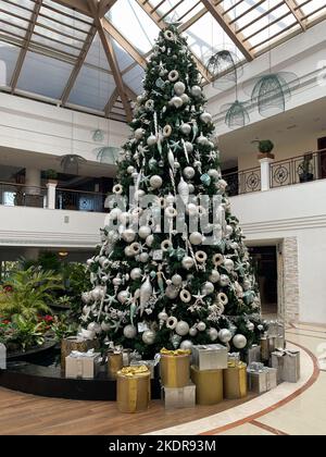 View of a tall Christmas tree beautifully decorated with many presents placed under the tree. Stock Photo