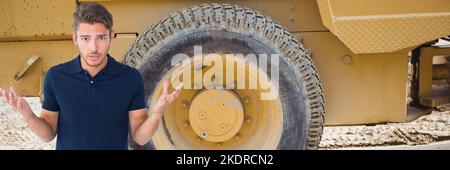 Portrait of frustrated caucasian young man shrugging shoulders against construction vehicle Stock Photo