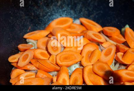 Carrot is cooked in cauldron on fire. Step by step cooking of Chorba. Stock Photo