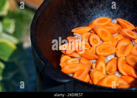 Carrot is cooked in cauldron on fire. Step by step cooking of Chorba. Stock Photo