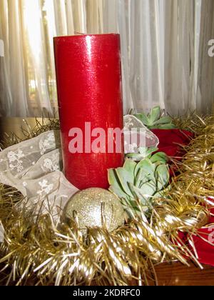 A single red unlit pillar candle, forming part of a Christmas table decoration Stock Photo