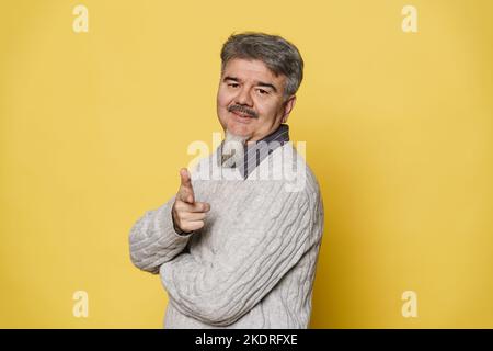 Senior grey man smiling and pointing finger at camera isolated over yellow background Stock Photo