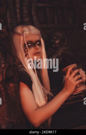 Viking woman with a mug in traditional warrior clothes inside a pub. Stock Photo