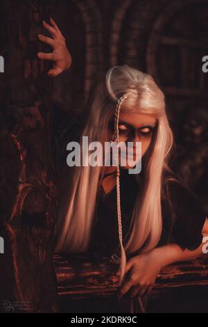 Viking woman with a mug in traditional warrior clothes inside a pub. Stock Photo