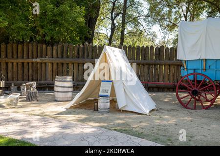 Genoa, NV, USA. 2022-09-17. Overnight canvas tent beside a blue Prairie Schooner wagon with red wheels at the Mormon Station Historic Park. Stock Photo