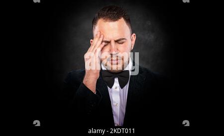 A man with a headache holds his head with his hand. Stock Photo
