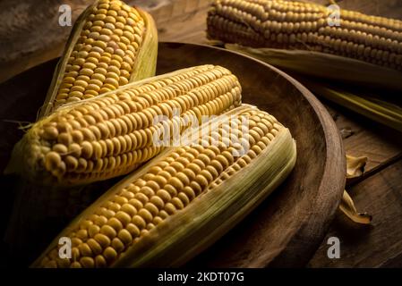 Group of corn cobs Zea mays in a wooden plate on rustic table Stock Photo
