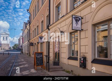 Helsinki, Finland - July 19, 2022: Yellow facade and entrance to El Fant Coffee and Wine bar on Katariinankatu street with rails and under blue clouds Stock Photo