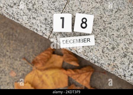 December 18 is written on a wooden white board which lies on a stone road in the street, a calendar Stock Photo