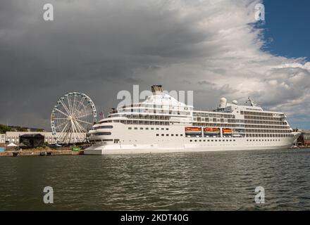 Helsinki, Finland - July 19, 2022: White Regent Seven Seas Navigator docked in port under rainy. dark sky. White skywheel in back Stock Photo