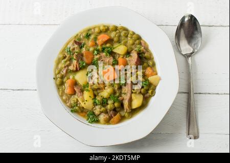 Plate with pea stew on white wooden background from above Stock Photo